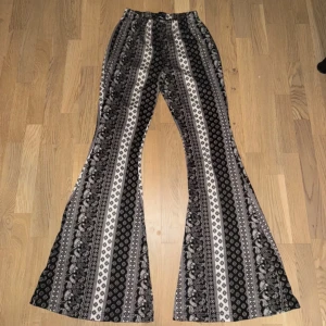 Mönstrade byxor med utsvängda ben - Säljer ett par snygga byxor med svart och vitt mönster. De har en skön, loose passform och är utsvängda vid benen för en retro look. Perfekta för både vardag och fest! 🖤🤍Fashionnova