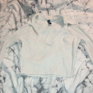 Vit ribbad tröja från H&M - Säljer en superfin vit ribbad tröja från H&M i storlek XS. Den har en snygg v-ringning och långa ärmar, perfekt för både vardag och fest. Tröjan är croppad och ger en trendig look. Passar perfekt till höst- och våroutfits!