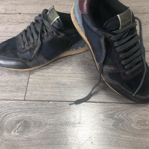 Valentino Garavani sneakers i blå och vinröd - Säljer ett par snygga Valentino Garavani sneakers i blått och vinrött. Storlek Uk 8 vilket är samma sak som storlek 43. Skorna är lite använda men de går inte o se på utsidan utan bara på sulan. Skorna kostade mig 8000kr men säljer dem för endast 3000 (dessa är en steal) om du har några funderingar/frågor är de ba att skriva🔒