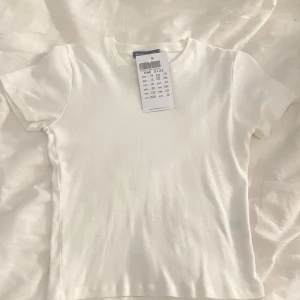 Vit kortärmad topp från brandy!! - Säljer en vit kortärmad topp i one size men skulle säga xs. Den är supermjuk och must-have basic! Oanvänd med prislapp kvar💞💞Nypris 198