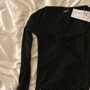 Svart långärmad topp från Gina Tricot - Snygg svart långärmad topp från Gina Tricot i storlek XS.Helt ny med prislapp kvar! Köp för 300kr, men säljer för 150. Säljer pga att den är för liten för mig som vanligtvis bär S