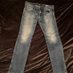 Replay jeans - Säljer ett par snygga blå jeansbyxor från Replay, modell Anbass. De har en klassisk femficksdesign och en lätt slitning på framsidan för en cool look. Perfekta för både vardag och fest! 🕺