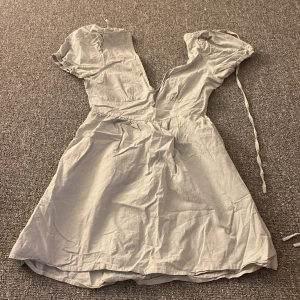 Ljusgrön klänning med knytband - Säljer en söt ljusgrön klänning med korta ärmar och knytband i midjan. Perfekt för sommardagar eller en avslappnad vårlook. Klänningen har en luftig passform och är gjord i ett mjukt material som känns skönt mot huden.