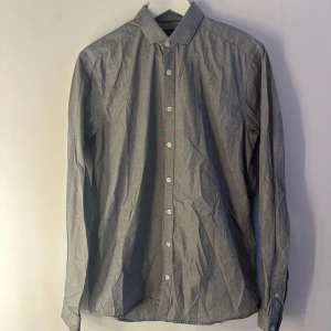 Grå skjorta Tiger of Sweden - En grå skjorta från Tiger of Sweden med långa ärmar och knappar framtill. Skjortan har en smal passform och en klassisk krage. Fint skick.