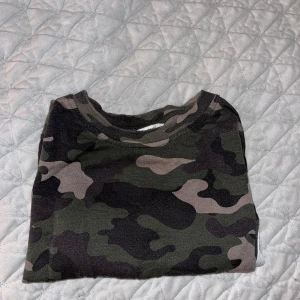Camouflage långärmad tröja - Säljer en cool camouflage långärmad tröja i gröna och svarta nyanser. Perfekt för en avslappnad stil. Tröjan har en magtröje passform och är superbekväm. Perfekt för höst och vår!