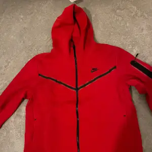 Säljer en snygg röd hoodie från Nike i storlek L. Den har en dragkedja framtill och en praktisk ficka på ärmen. Perfekt för höst och vår, med en sportig look och bekväm passform. Huvan ger extra värme och stil. Passar både till träning och vardag! Priset kan diskuteras 