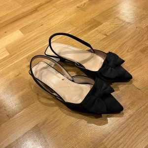 Svarta rosett klackar - Klackarna är i använt skick och ena bandet har lossnat så jag har försökt laga med superlimm. Men annars jättefina. Storlek 38