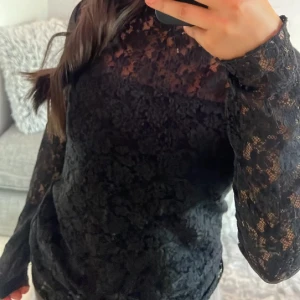 Svart spetsblus från KappAhl - Säljer en elegant svart spetsblus från KappAhl i storlek XS. Blusen har långa ärmar och en tight passform, perfekt för festliga tillfällen. Den är tillverkad i ett vackert spetsmaterial som ger en sofistikerad look. Använd den för att lyfta din outfit till nästa nivå! Kan alltid gå ner i pris vid snabb affär❤️
