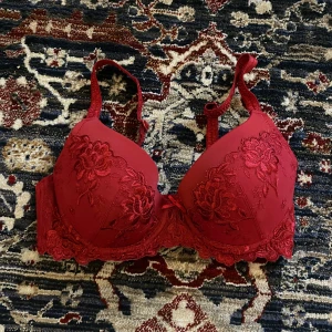 Röd spets-bh från Triumph - Säljer en elegant röd bh från Triumph med vacker spetsdetalj. Den har justerbara axelband och en klassisk hakknäppning bak. Perfekt för att känna sig extra fin till vardags eller speciella tillfällen. 💃 I my jet bra skick, det står tyvärr inge storleken men skulle gissa på C, D kupa!