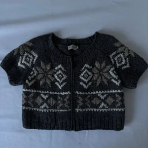 Grå stickad kofta från Moncler - Säljer en superfin grå stickad kofta från Moncler med ett snyggt mönster i beige och vitt. Den har korta ärmar och en dragkedja framtill. Perfekt för höst och vinter! 🧶✨ Nypris ca 5000