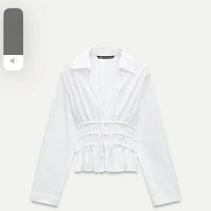 Vit blus från Zara - Säljer en superfin vit blus från Zara. Den har långa ärmar och snygga knytband i midjan som ger en smickrande passform. Perfekt för både vardag och fest! 💫