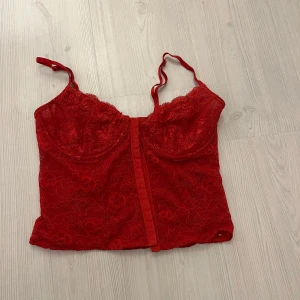 Röd spetskorsett - Säljer en superfin röd spetskorsett med justerbara axelband. Den är inte genomskinlig vid brösten så de är extra lager tyg. Använd ett par gånger men i mycket bra skick! 