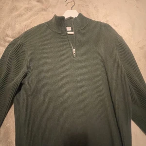 Grön ribbad tröja från John Henric - Säljer en snygg grön ziptröja från John Henric i storlek L.  perfekt för både höst och vinter. Den är långärmad och gjord i ett mjukt material!
