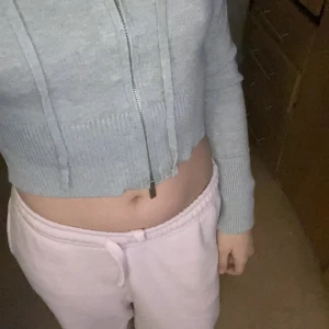 Grå croppad hoodie - Säljer en supermjuk och bekväm grå croppad hoodie med dragkedja. Perfekt för en avslappnad stil eller mysiga dagar hemma. Den har långa ärmar och en ribbad kant som ger en snygg passform. Passar perfekt till dina favoritjeans eller mjukisbyxor!