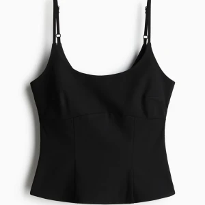 Svart linnetopp med justerbara axelband - Snygg och stilren svart linnetopp med justerbara axelband. Perfekt för både vardag och fest. Toppen har en enkel och elegant design som gör den lätt att matcha med olika outfits.