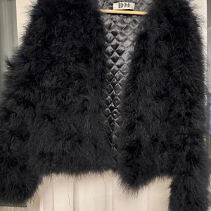Svart pälsjacka från DM - Säljer en supercool svart pälsjacka från DM. Den är fluffig och perfekt för att göra ett statement på festen. Insidan är quiltad vilket ger extra värme och stil. Jackan är i mycket bra skick och passar perfekt till höst och vinter. Perfekt för dig som vill sticka ut!