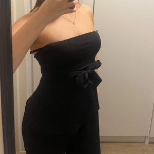 Svart tubtopp med knyt - Snygg svart tubtopp i mjukt material med separat knytrosett. Figurnära passform! 