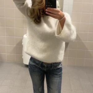 Vit stickad tröja i ull - Mysig och stilren vit stickad tröja i ull. Perfekt för kyliga dagar med sin varma och sköna känsla. Tröjan har en normal passform och långa ärmar, vilket gör den idealisk för både vardag och fest. Ett måste i garderoben för höst och vinter! Tröjan är knappast använd där av att jag säljer den! Pris kan diskuteras 