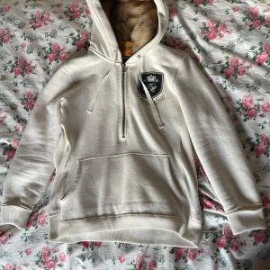 Pälshoodie - Säljer en supermysig vit hoodie från Tommy Hilfiger med en fluffig foder i luvan. Den har en snygg broderad logga på bröstet och en praktisk dragkedja framtill. Perfekt för kyliga dagar när du vill vara både varm och stilren. 🙏🤍