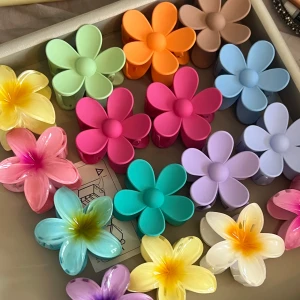 Färgglada hårklämmor i blomform - Säljer ett set med färgglada hårklämmor i form av blommor. Klämmorna kommer i olika färger som rosa, blå, lila, grön, gul och orange. Perfekta för att ge en lekfull touch till din frisyr. 29kr/st 