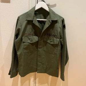 Grön militärjacka med US Army-märke - Säljer en 🟩militärjacka med US Army-märke. Strl S. Köpt på en vintage butik i Italien. Fler bilder går att fixa.