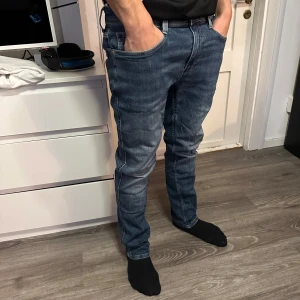 Levis 521 Tapered Fit Jeans - Snygga Levis 521 jeans i en klassisk blå färg. De har en tapered fit som ger en modern look och är perfekta för en avslappnad stil. Midjan är midwaist och storleken är 32/30. Perfekta för dig som vill ha en stilren och bekväm byxa.