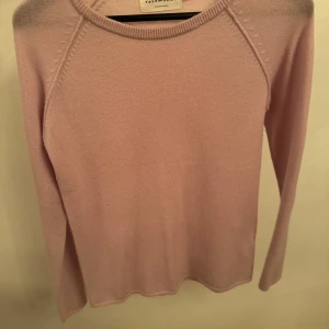 Rosa stickad tröja från Rosemunde - Säljer en mjuk och stilren gammalrosa stickad tröja från Rosemunde. Tröjan är tillverkad i en lyxig blandning av ull och kashmir, vilket gör den perfekt för kyligare dagar. Den har långa ärmar och en klassisk rund halsringning.