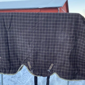 Rhino utetäcke med halvhals stl 115 - Utetäcke med halvhals 370g från rhino horseware. Täcket är otvättat på bilderna men tvättas innan köp. Storlek 115 men suttit på nätt c-ponny som har stl 125 i andra täcken förutom horsewaretäcken. Fint skick och sparsamt använt.