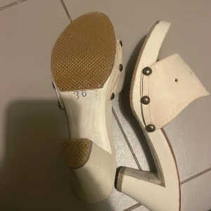 Vita klackskor  - Snygga vita klackskor med dekorativa nitar och utskurna detaljer. Skorna har en stabil klack och är i storlek 36. Perfekta för att ge en stilren touch till din outfit. Skorna är vintage från 1920 talet!!!