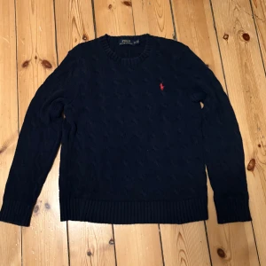 Mörkblå stickad Ralph Lauren tröja - Säljer en mörkblå stickad tröja från Polo Ralph Lauren. Den är knappt använd och i bra skick.
