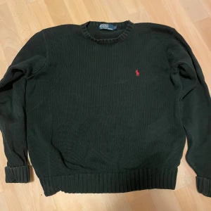 Svart stickad tröja från Ralph Lauren - Säljer en stilren svart stickad tröja från Ralph Lauren med det klassiska röda logotypbroderiet på bröstet. Tröjan har långa ärmar och ribbade muddar vid ärmslut och nederkant. Perfekt för kyligare dagar. Den är bra skick och varsamt använd. Pris går att diskutera
