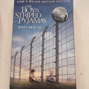 The Boy in the Striped Pyjamas - Boken 'The Boy in the Striped Pyjamas' av John Boyne är en gripande berättelse som nu även är en storfilm. Omslaget visar två pojkar vid ett stängsel, vilket speglar bokens innehåll,