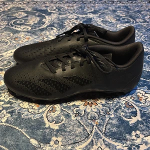 Svarta fotbollsskor från Adidas - Snygga svarta fotbollsskor från Adidas med snörning och mönstrad sula för optimalt grepp. Perfekta för fotbollsplanen med en stilren design.    Dessa skor har aldrig använts säljer de eftersom de var för små för mig, de är i storlek 44 men passar som 43.   Vid frågor kontakta 