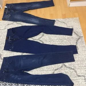 Tre par jeans som har mörkblå färg  - Säljer tre par snygga  jenas . De har en klassisk design med fem fickor och knappgylf. Perfekta för en avslappnad stil.