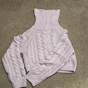 Ljuslila stickad polotröja från Gina Tricot - Mysig ljuslila stickad polotröja från Gina Tricot med flätmönster. Tröjan har en hög polokrage och långa ärmar, perfekt för kyliga dagar. Den är väldigt varm och den sticks inte!