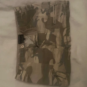 Camouflage kjol från Old Khaki - Säljer en cool camouflage kjol från Old Khaki. De har flera praktiska fickor med dragkedjor och knappar, perfekt för vardagslook🩷passar mig som bär w26/27