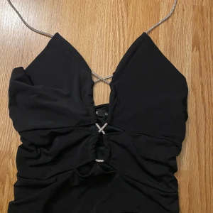 Svart halterneck topp med strassdetaljer - Snygg svart halterneck topp med glittrande strassband och rynkade detaljer. Perfekt för en kväll ute eller festliga tillfällen. Storlek xs men passar mig som är xs/s 🥰🤩