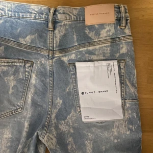 Purple Brand Jeans - Snygga blå jeans från Purple Brand med unikt blekt mönster. De har en klassisk femficksdesign och knappgylf. Tillverkade i bomull med en läderpatch baktill.