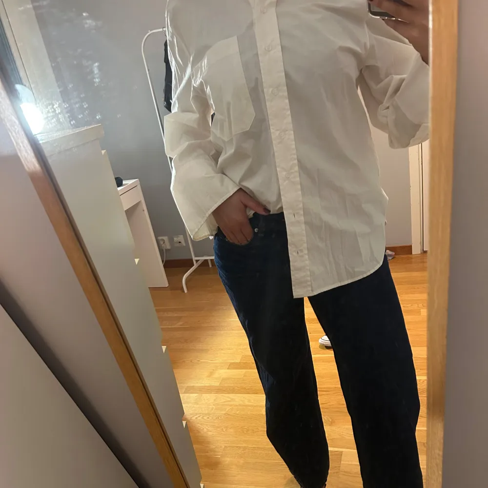 Säljer en klassisk vit skjorta med långa ärmar och två bröstfickor. Skjortan har en oversized passform och knäppning framtill. Perfekt för en stilren look. Nyskick! . Paidat.
