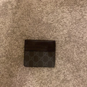 Mönstrad plånbok - Snygg och kompakt plånbok med ett diskret mönster. Perfekt för att hålla dina kort och kontanter organiserade. Den har flera kortfack och en stilren design.