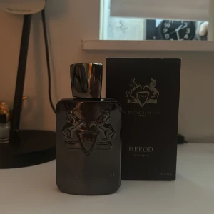 Herod Eau de Parfum från Parfums de Marly - Elegant och maskulin parfym i en stilren mörk flaska med silverdetaljer. Herod är en doft med rika och kryddiga noter, perfekt för den som vill utstråla självsäkerhet och stil. Flaskan rymmer 125ml och har kvar 100 ml ut av denna exklusiva doft.