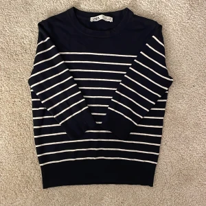 Stickad T-shirt  - Säljer en snygg randig tröja från Zara i marinblått och vitt. Tröjan har trekvartsärmar och en klassisk rund halsringning. Perfekt för en stilren look!
