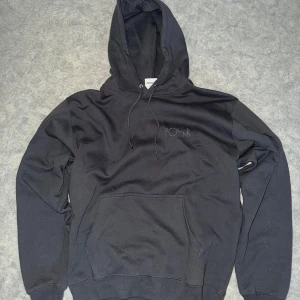 Grå hoodie från Polar - Säljer en svart hoodie från Polar med en stor logga på ryggen och en mindre på bröstet. Den har en klassisk känguruficka och justerbar huva. Perfekt för en avslappnad stil.