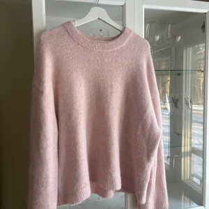 Rosa stickad tröja från Gina Tricot - Mysig rosa stickad tröja från Gina Tricot i storlek M. Tröjan har en rund halsringning och långa ärmar, perfekt för kyliga dagar. Den är gjord i ett mjukt material som känns skönt mot huden.