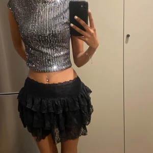 Glittrig silver topp - Snygg glittrig silver topp med korta ärmar och en tight passform. Perfekt för festliga tillfällen med sitt iögonfallande paljettmönster.