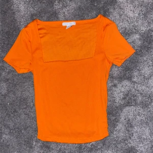 Orange kortärmad topp från new yorker - Snygg orange topp från new yorker med korta ärmar och en fyrkantig halsringning. Perfekt för en färgglad look.