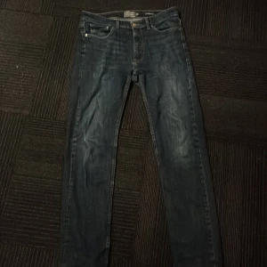 Mörkblå jeans från Dressmann - Snygga mörkblå jeans från Dressmann med en klassisk femficksdesign. De har en knappgylf och är i en regualar fit. Perfekta för en avslappnad stil.  Blev ett hål på knät så dom syddes ihop syns inte mycket när man har på dem. Nypris 600.