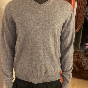 Grå kashmirtröja från Cashmeres - Säljer en elegant grå kashmirtröja från Cashmeres. Tröjan har en v-ringad design och är tillverkad av 100% kashmir. Modell 185 cm och 75 kg. Använder Herr Medium