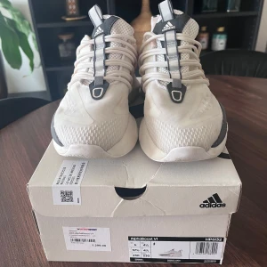 Adidas Alphaboost V1 sneakers - Säljer ett par Adidas Alphaboost V1 sneakers i nyskick. Skorna är vita med ljusrosa och grå detaljer och har en modern design med snörning. De är perfekta för träning eller vardagsbruk och kommer i originalkartong. Storlek 37. 