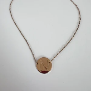 Guldigt halsband - Ett guldigt halsband med bokstaven N 💛 Inköpt från Chiquelle.  (ALDRIG ANVÄNT)  Längd: 40-46 cm